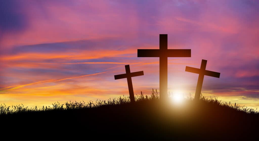 Three Christian cross on hill at sunset.